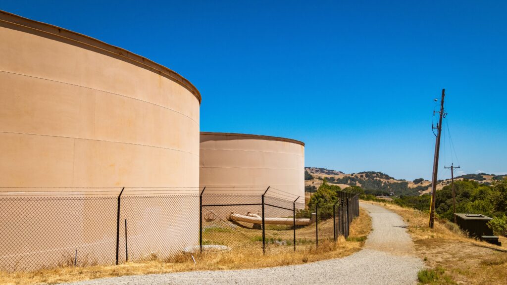 large storage tanks in a rural landscape with hills