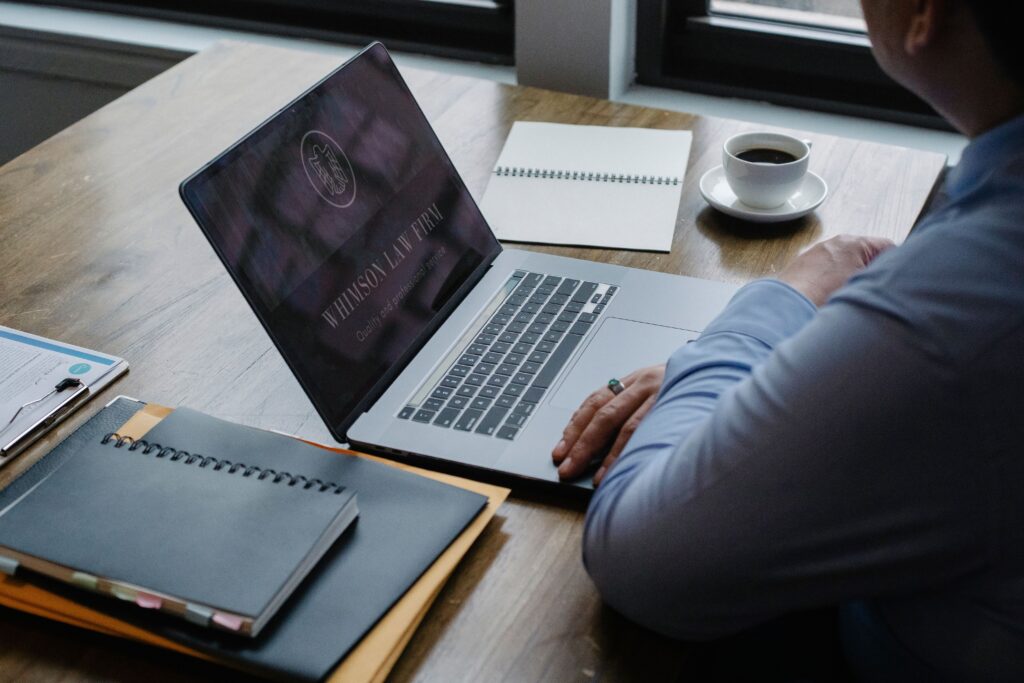 person working on a laptop at a desk with notebooks